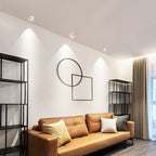 White units of this Clérachic downlight light the same living room, tan leather sofa and circular wall art visible.