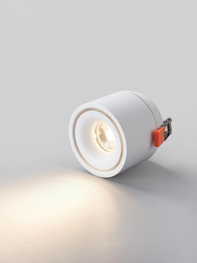 Close view of this Clérachic downlight in white, angled low, its lens lit and its spring clip visible at the side.