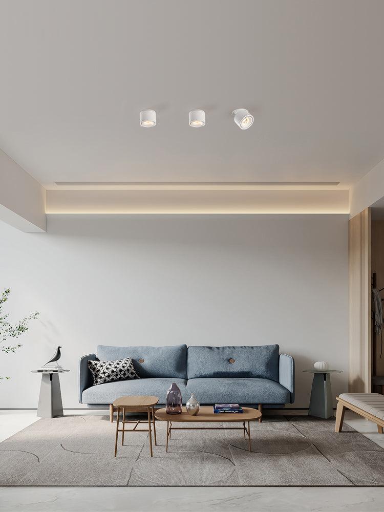White units of this Clérachic downlight line a living room ceiling above a blue sofa and a slim console table.