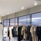 A row of assorted ceiling downlights, in shapes different from this Clérachic fixture, lights a clothing rail in a bright retail space.