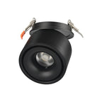 Close view of this Clérachic downlight in black, angled low, its lens lit and spring clips extended above.