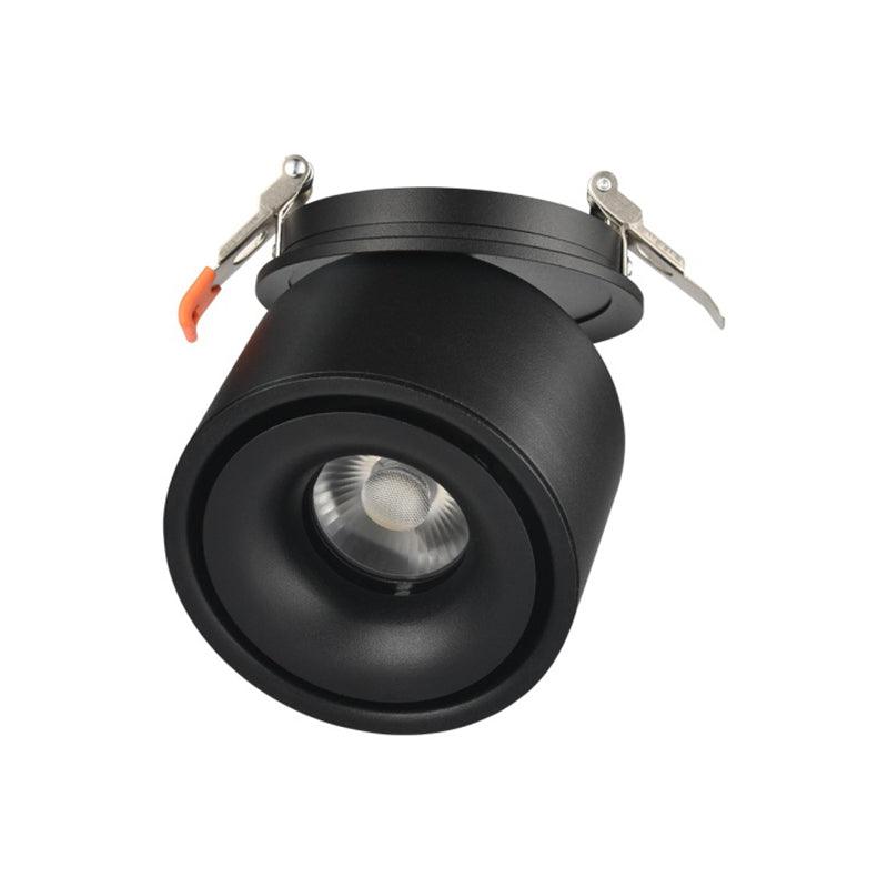 Close view of this Clérachic downlight in black, angled low, its lens lit and spring clips extended above.