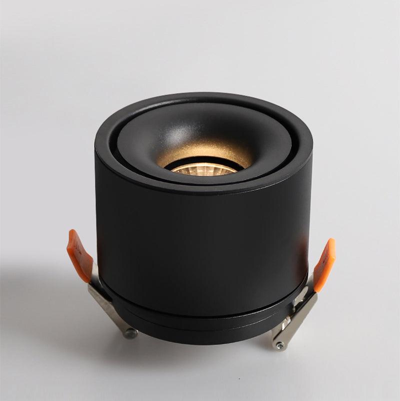 Close view of this Clérachic downlight in black, angled forward, its lens lit and rimmed with a thin amber ring.