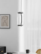 A single wide-cylinder Clérachic pendant hangs near a sheer curtain above a round table set with a mug.