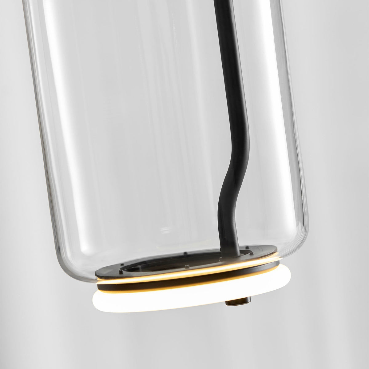 Close view from below of this Clérachic pendant's glass cylinder, its LED ring glowing warm at the base.
