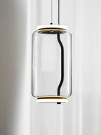 A single wide-cylinder Clérachic pendant hangs close against a sheer curtain, its black cord visible inside the glass.