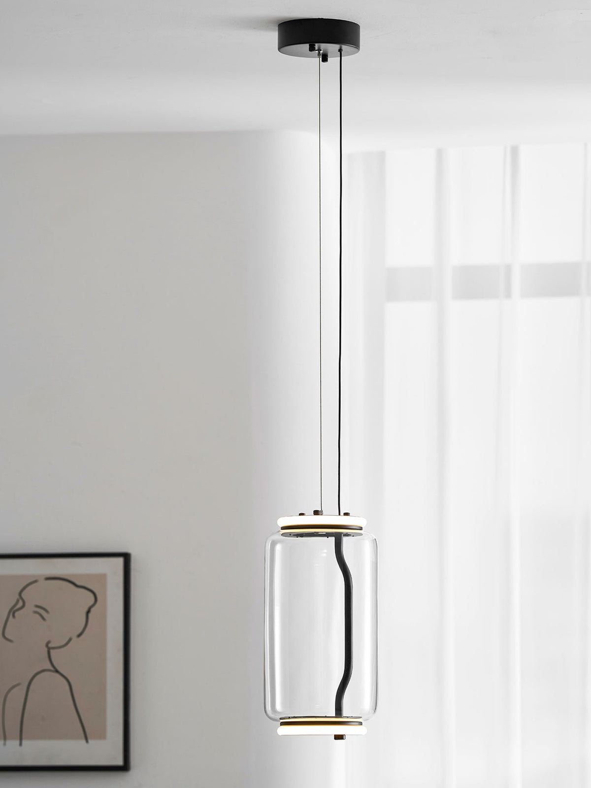 A single wide-cylinder Clérachic pendant hangs in a white room beside a line-drawn portrait print.