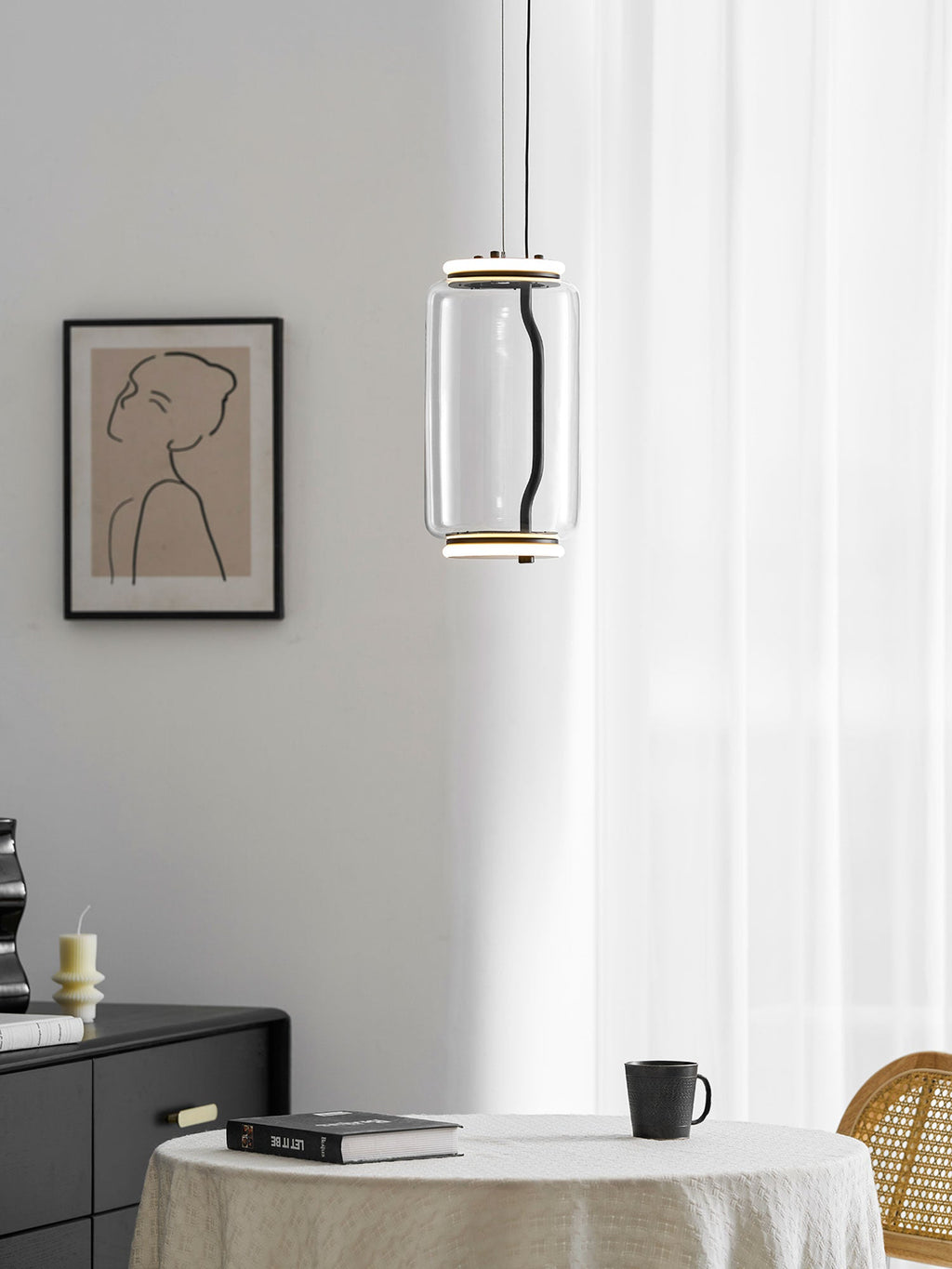 A single wide-cylinder Clérachic pendant hangs near a sheer curtain and a framed portrait print.