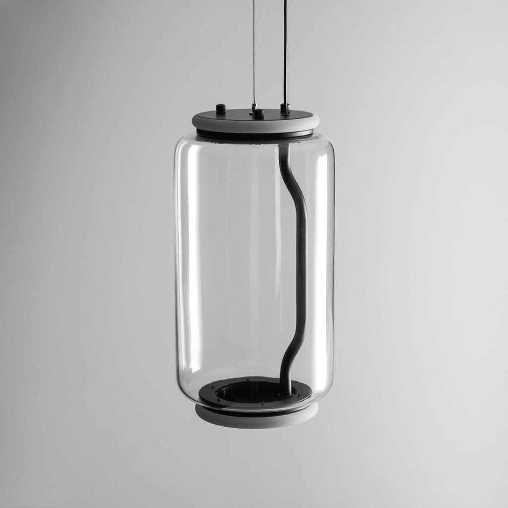 Close view of this Clérachic pendant's wide glass cylinder and black base cap on a plain grey background.
