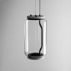 Close view of this Clérachic pendant's wide glass cylinder and black base cap on a plain grey background.