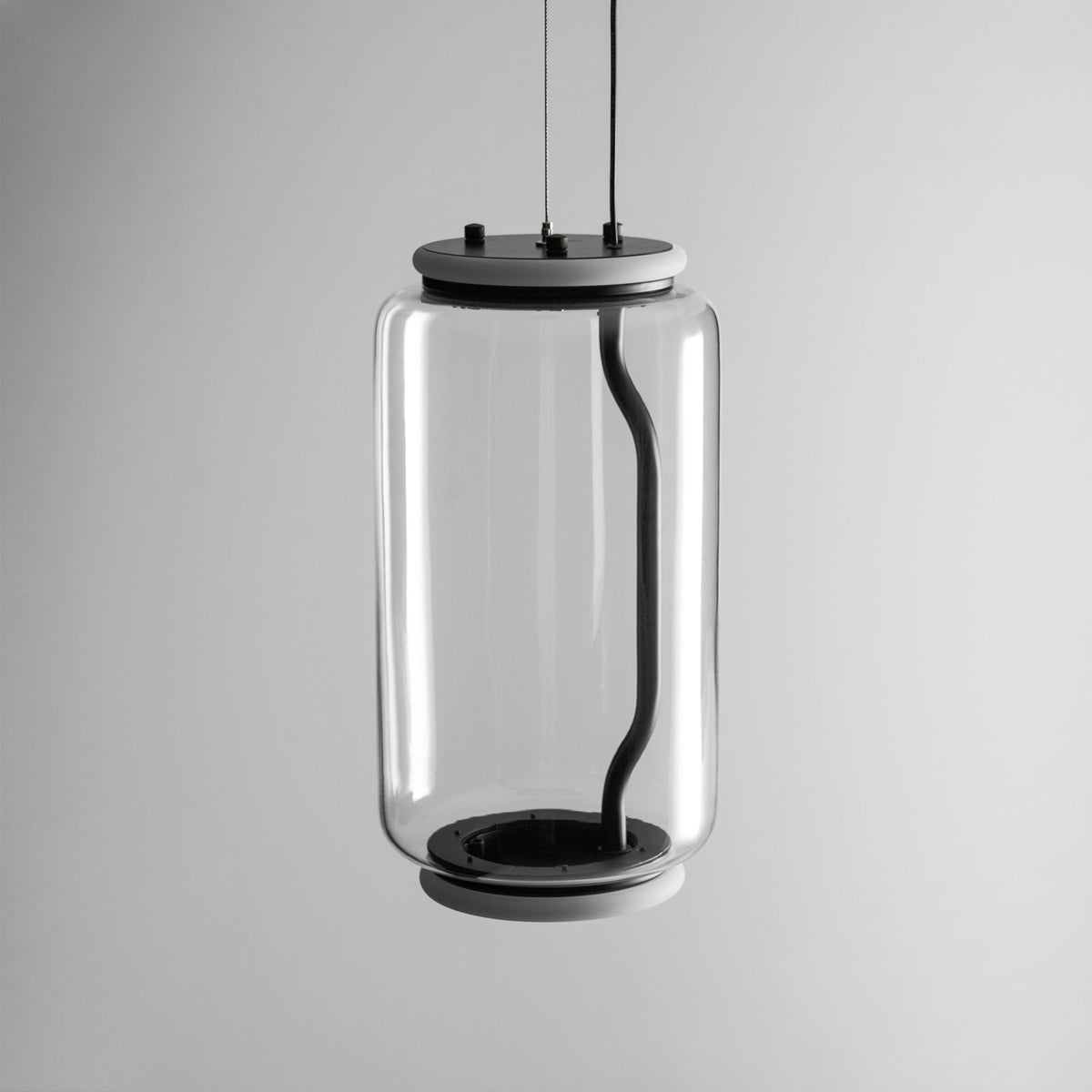 Close view of this Clérachic pendant's wide glass cylinder and black base cap on a plain grey background.
