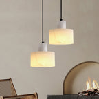 Hand-cut alabaster pendant light lit warmly on a plain backdrop
