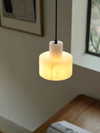 Alabaster pendant light lit above a bedside setting