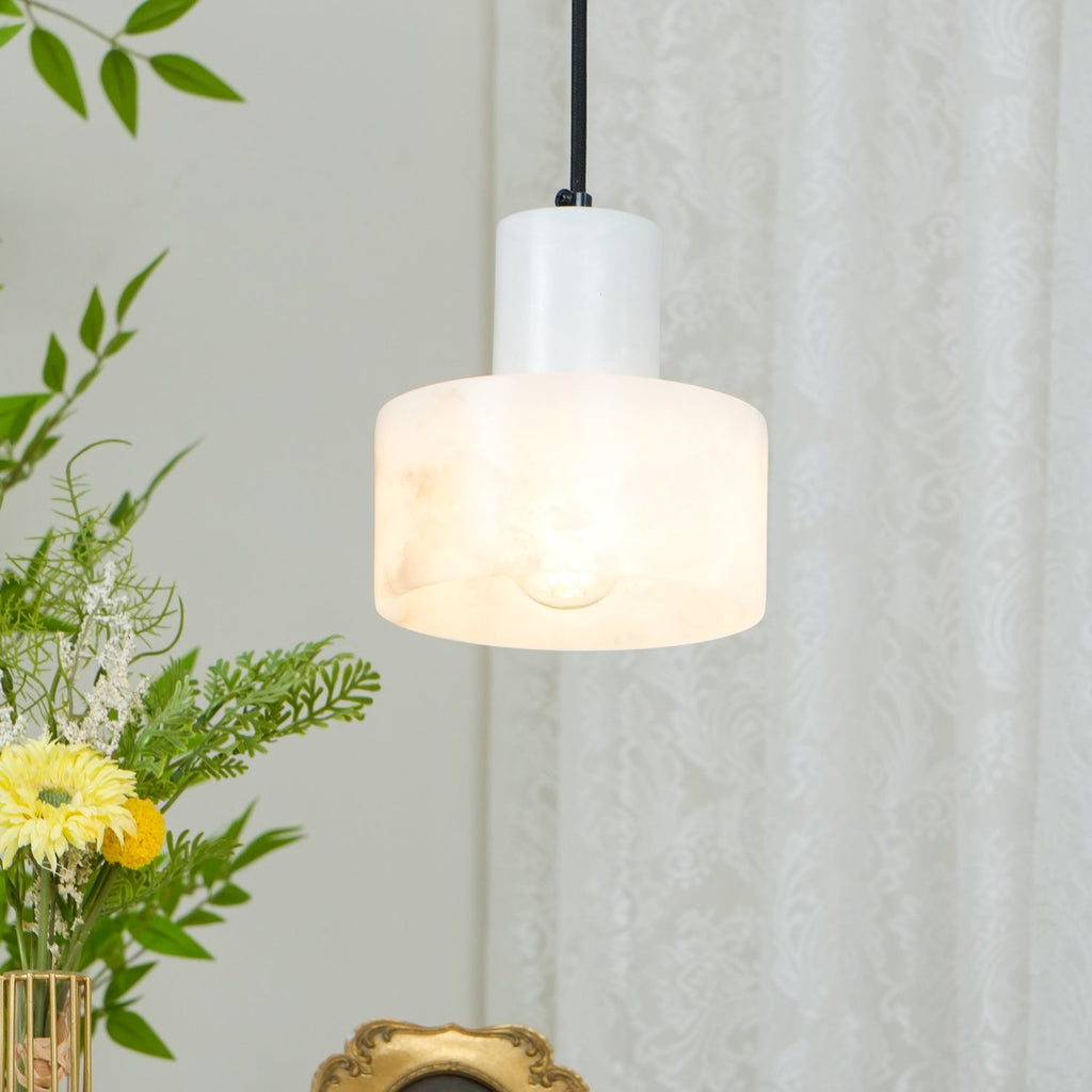Alabaster pendant light glowing softly above a nightstand