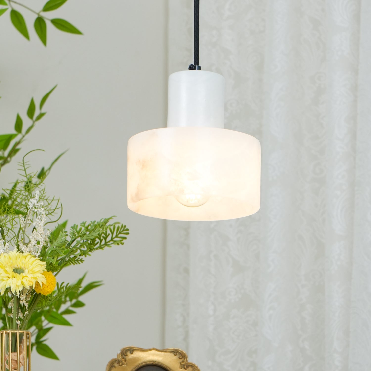 Alabaster pendant light glowing softly above a nightstand