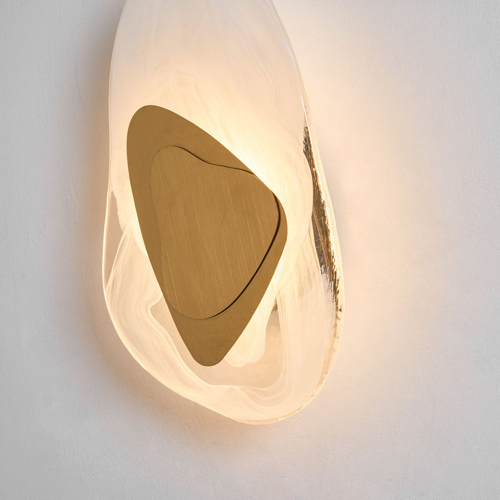Wall lamp glowing warmly beside a piece of decor