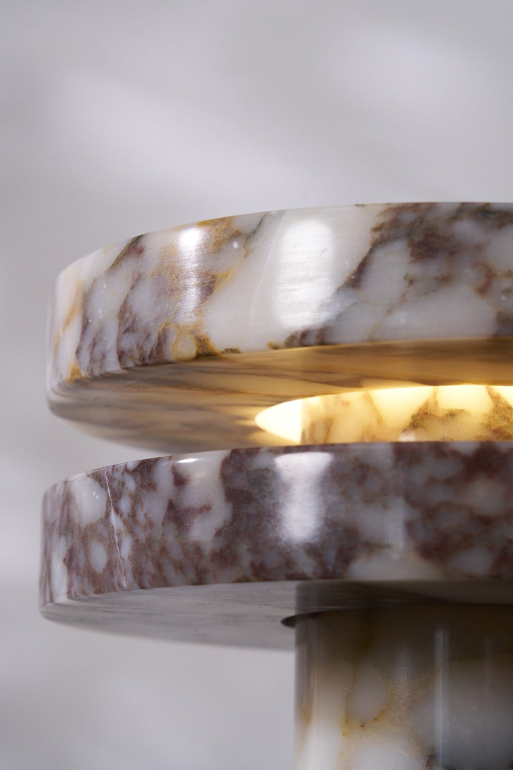 Rotated close-up of the Clérachic lamp's stacked discs seen nearly edge-on, the warm glow visible between them.
