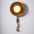 Cropped close on white, this top-down view captures only the glowing shade and tray rim of the Clérachic sconce.