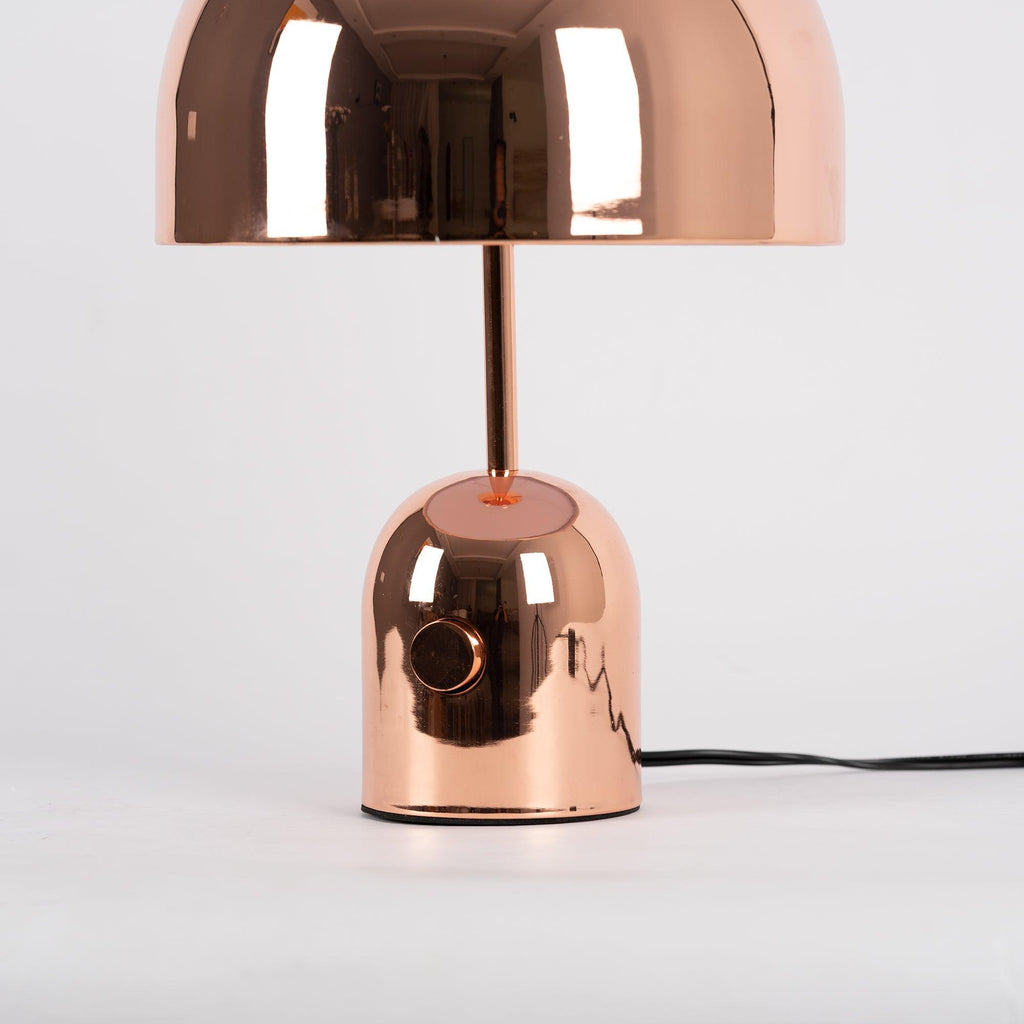 A close mid-shot of this Clérachic rose gold table lamp shows its stem, shade and visible cord against grey.