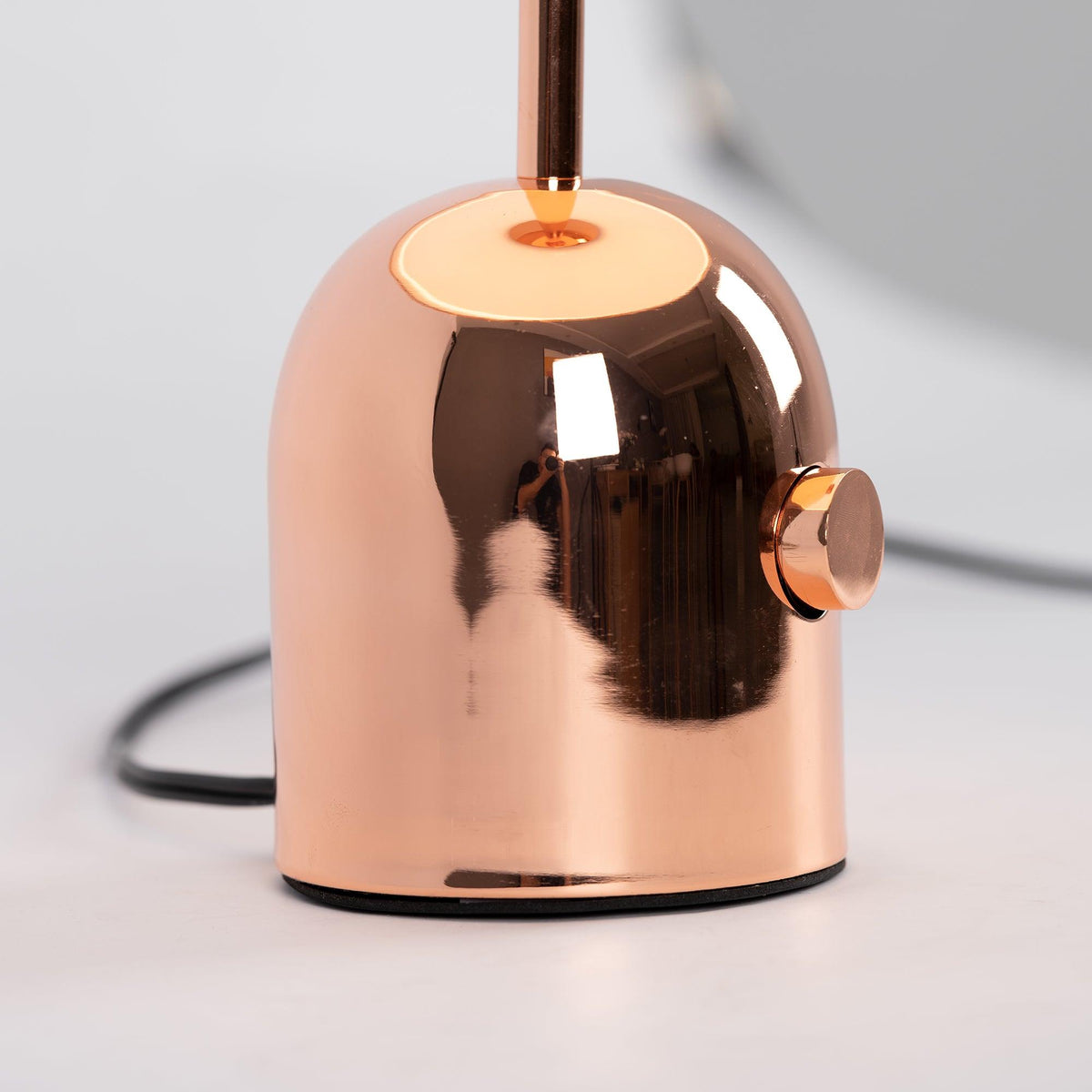 An extreme close-up shows the push-button switch on the base of this Clérachic rose gold table lamp.