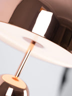 An extreme close-up from below shows light glowing through the stem inside this Clérachic rose gold lamp's dome shade.