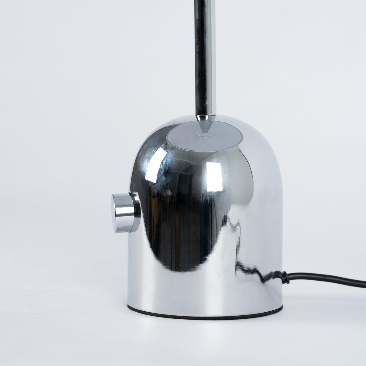 A close-up shows the push-button switch and cord where the dome meets the base on this Clérachic chrome table lamp.