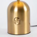 An extreme close-up shows the textured brushed gold base and dial switch of this Clérachic table lamp.