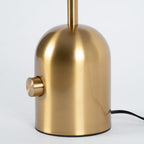 A close-up shows the large knob switch on the brushed gold base of this Clérachic table lamp, cord trailing right.