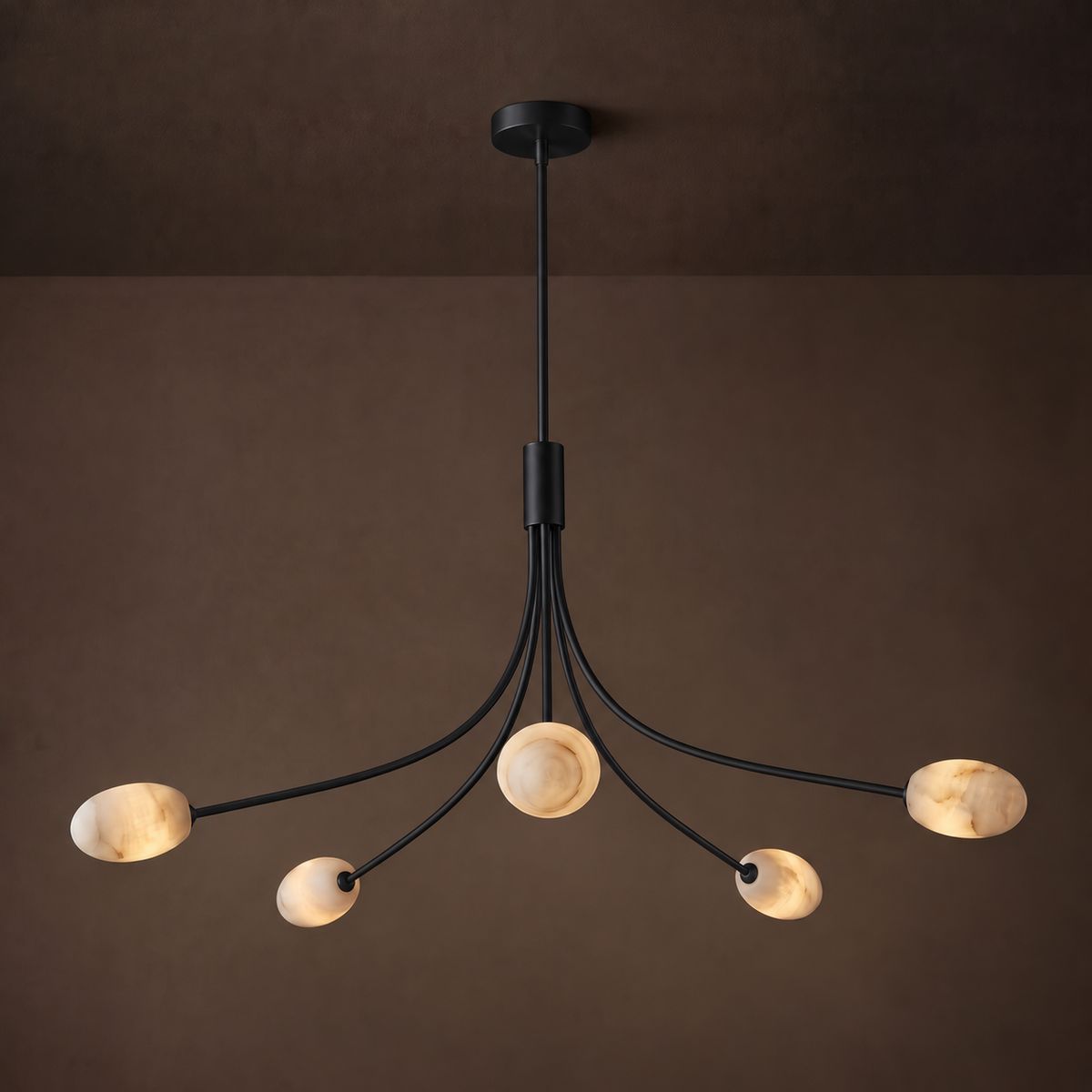 This Clérachic chandelier in matte black stands against a warm brown backdrop, its alabaster discs glowing softly.