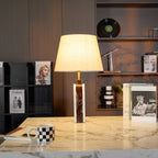 The Clérachic marble table lamp centred on a stone side table, a dark bookshelf and vinyl record visible behind.