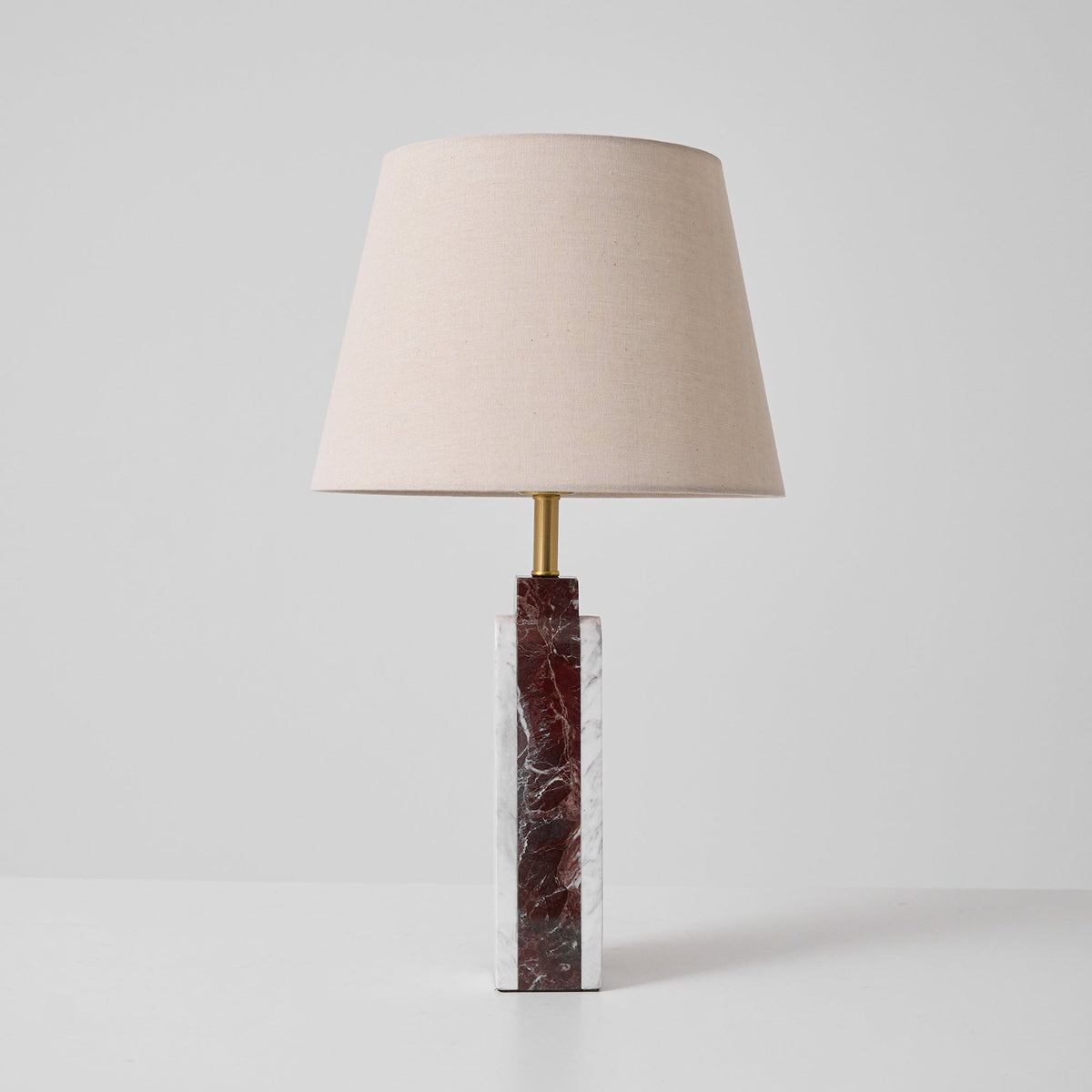 A Clérachic table lamp on a studio background, dark veined marble base catching light beneath the fabric shade.