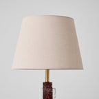 An extreme close-up of the Clérachic table lamp's shade and brass neck, its stone base just visible below.