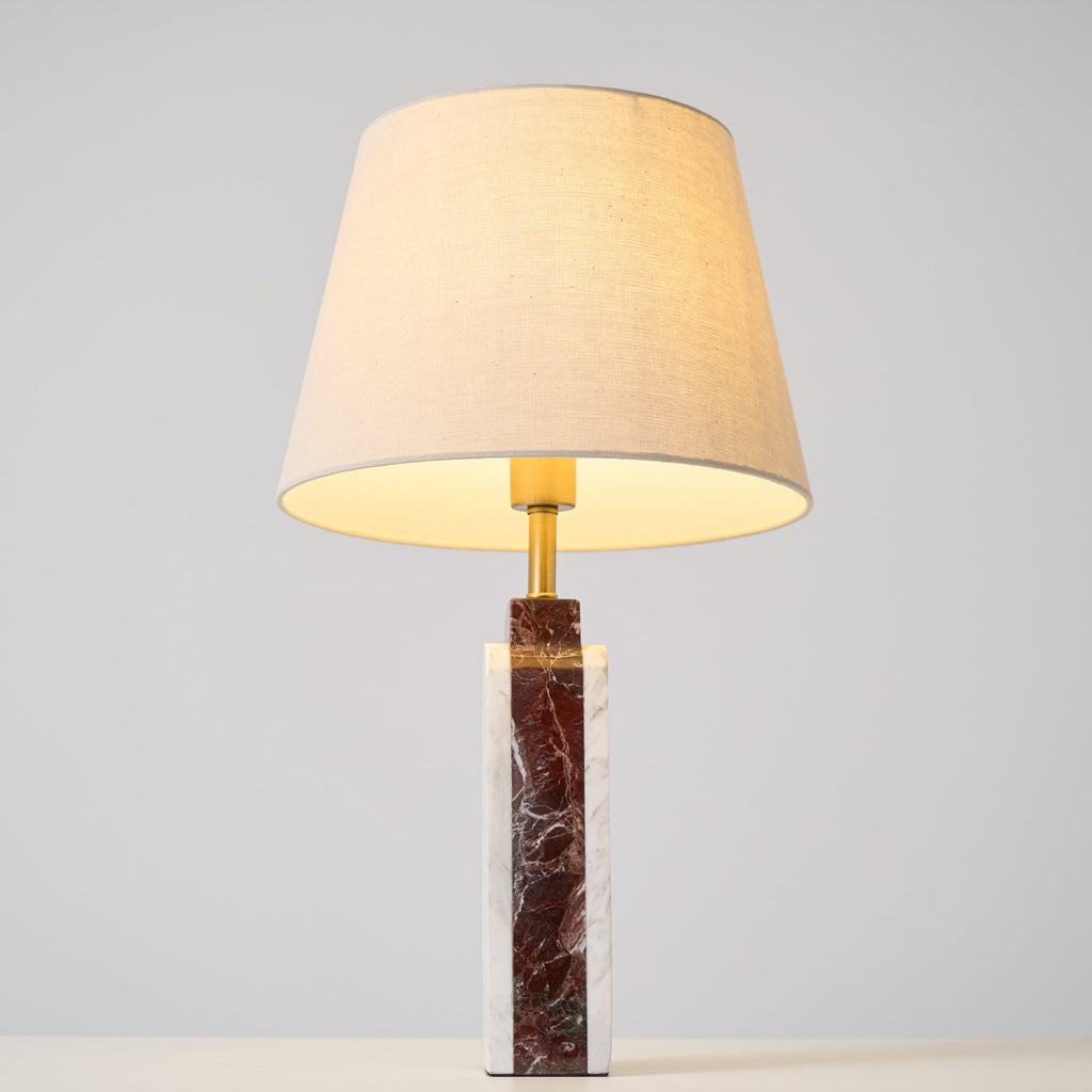 The Clérachic marble table lamp lit on a studio background, the shade's pale interior glowing around the bulb.