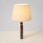 A close view from below the lit shade of the Clérachic table lamp, its warm interior bright against the base.