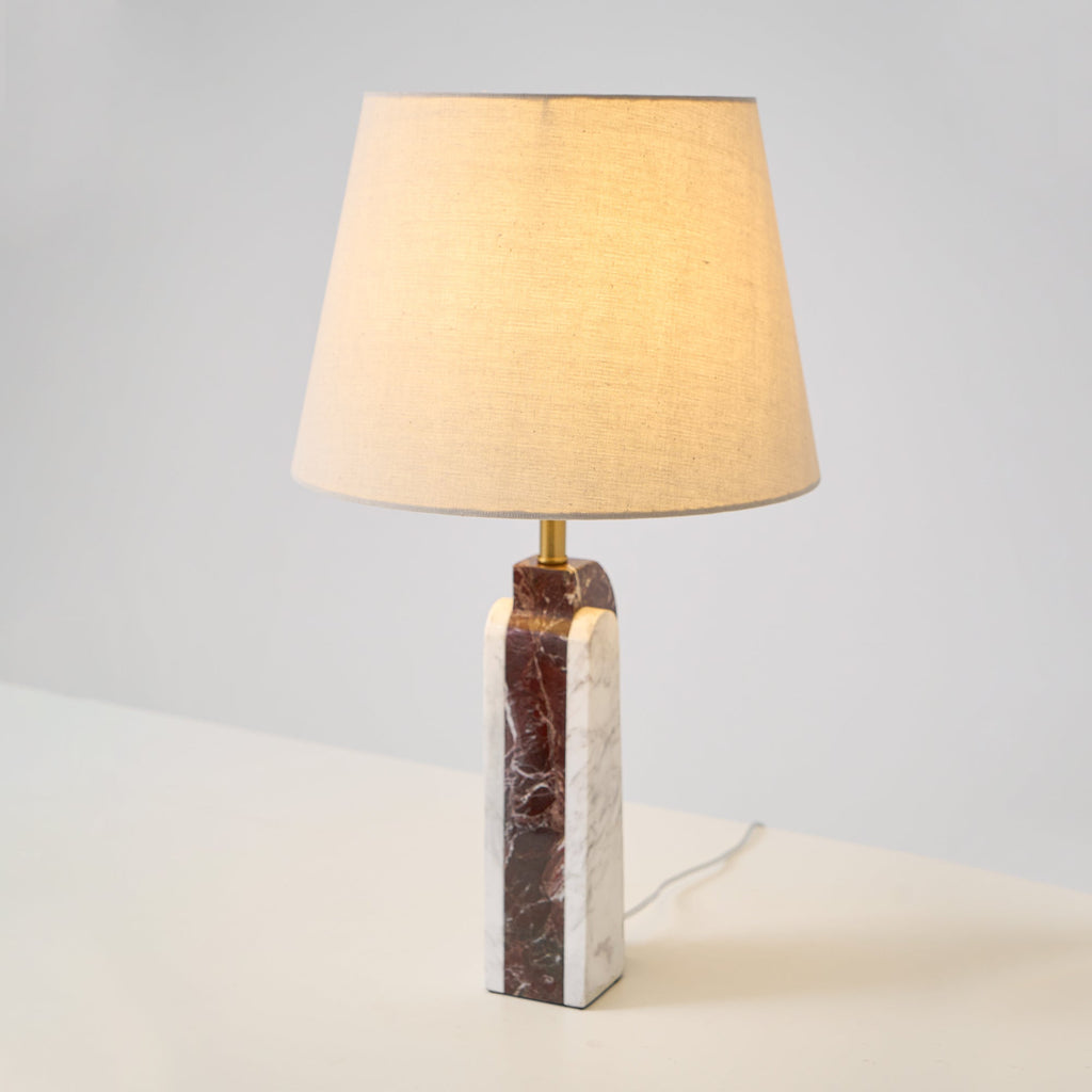 Clérachic's table lamp glows on a plain studio background, dark marble base grounding the beige fabric shade.