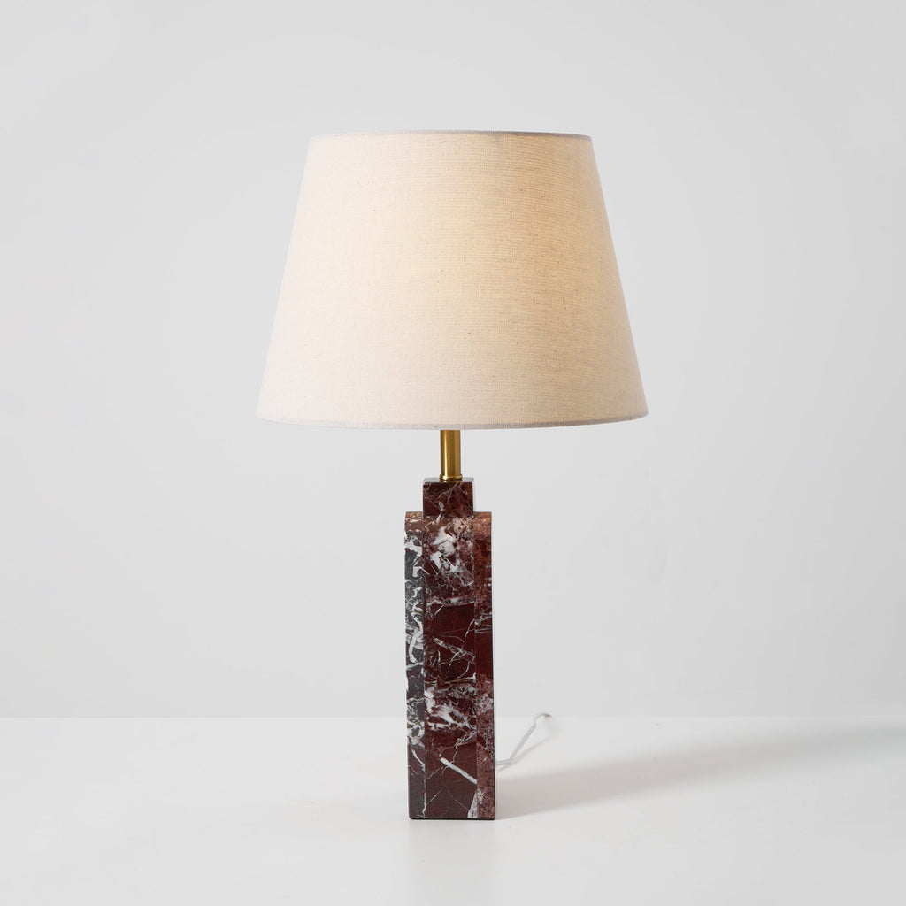 Softer lighting on the Clérachic table lamp, the shade warm against a pale wall and the cord trailing from the marble base.
