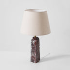 The same Clérachic table lamp photographed with its cord visible, the red marble base veined in white below a linen shade.