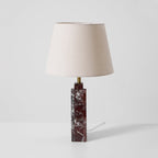 A slight angle on the Clérachic table lamp, the square marble base catching light along one edge beneath the cream shade.