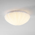 Stepped back for a wider view, this Clérachic ceiling light shows its full ribbed profile glowing warm against a grey wall.