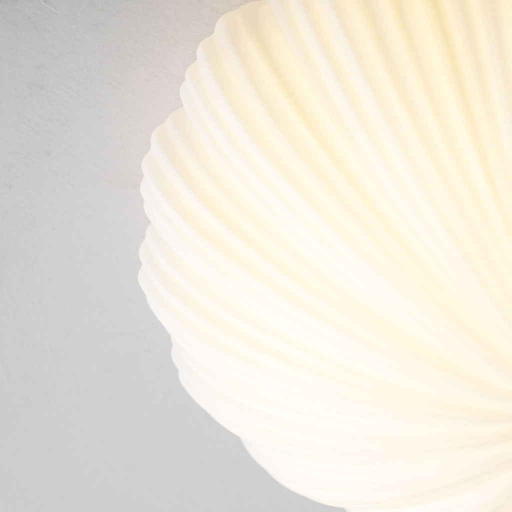 Close view of the same pleated ribs on this Clérachic ceiling light, now glowing warm from within.