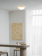 Glowing warm white in a room corner, this Clérachic ceiling light sits above sheer curtains and pale walls.