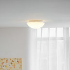 A wider view shows this Clérachic ceiling light glowing warm white above a room with sheer curtains and a floral painting.