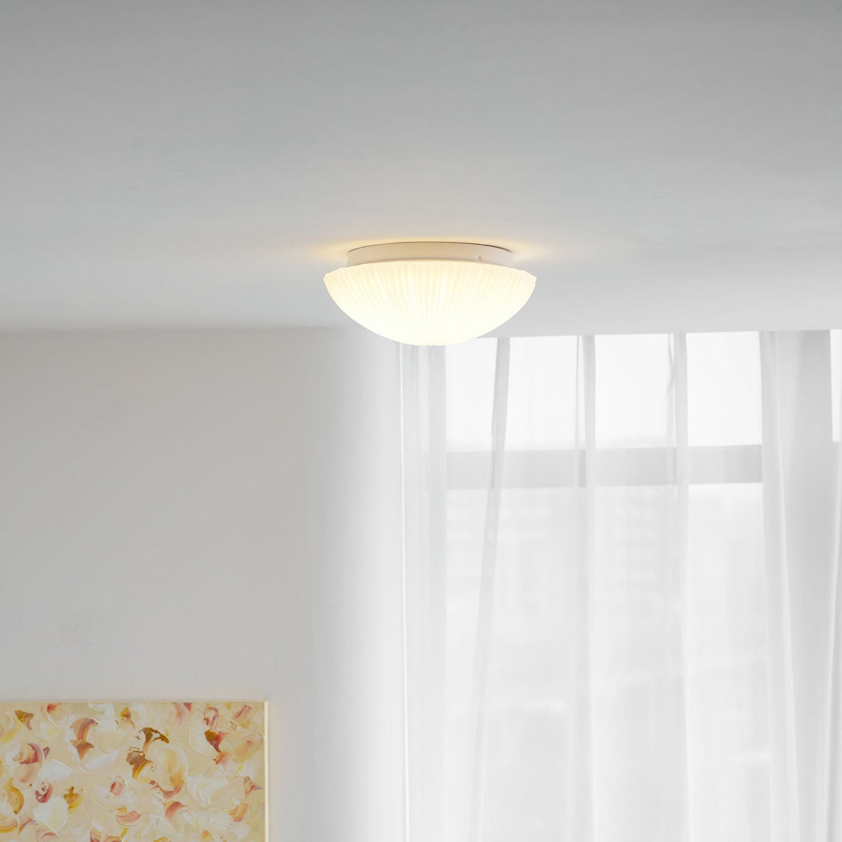 A wider view shows this Clérachic ceiling light glowing warm white above a room with sheer curtains and a floral painting.