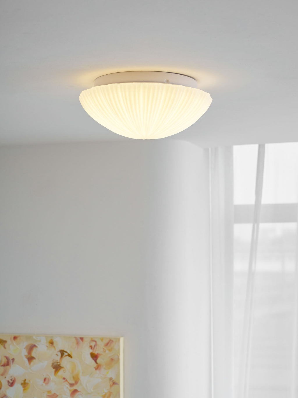 Closer in, this Clérachic ceiling light glows warm white above a dining table and chair.
