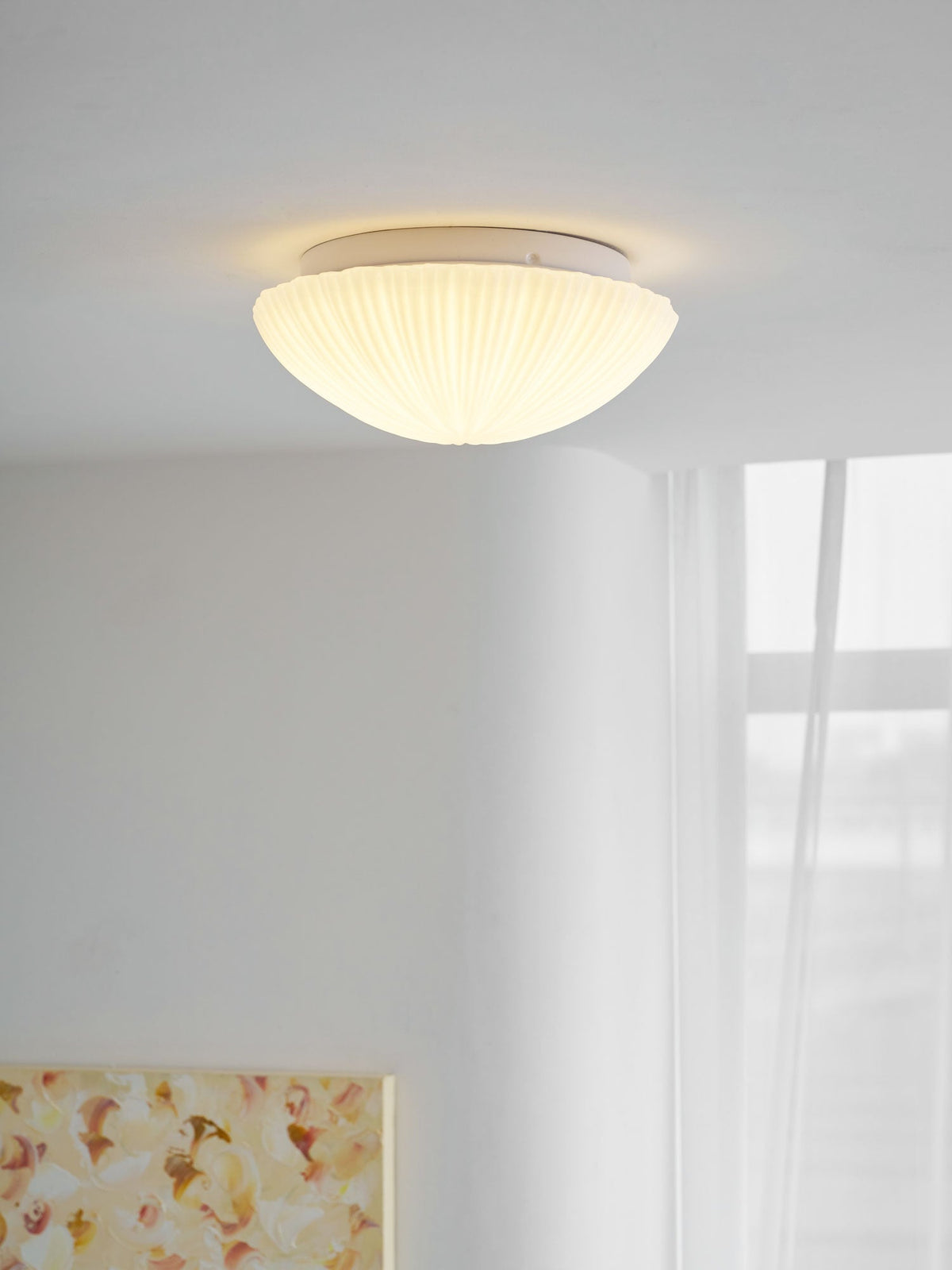 Closer in, this Clérachic ceiling light glows warm white above a dining table and chair.