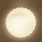 Close frontal view of the radiating ribs on this Clérachic ceiling light, glowing warm against a brown wall.