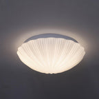 This Clérachic ceiling light glows warm white in side profile against a dark charcoal backdrop.