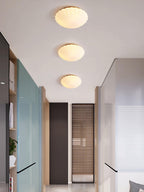 A row of this Clérachic ceiling light lines a hallway with a mirror and dark teal-framed doors, all glowing warm.