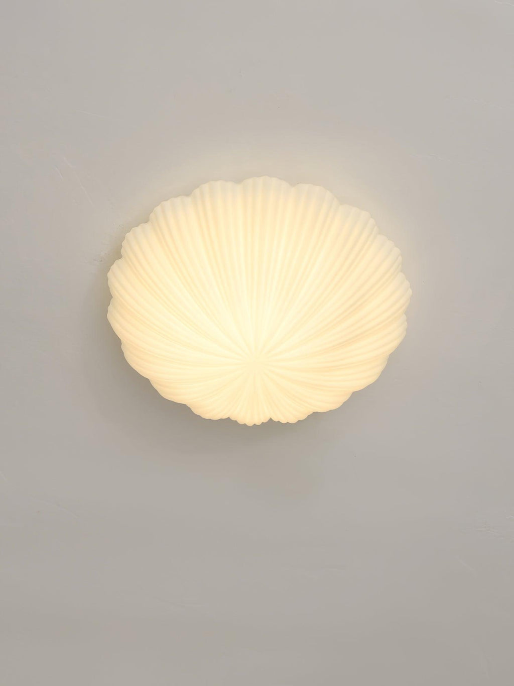 Mounted to this wall rather than a ceiling, the ribbed shade of this Clérachic light glows warm white in side profile.