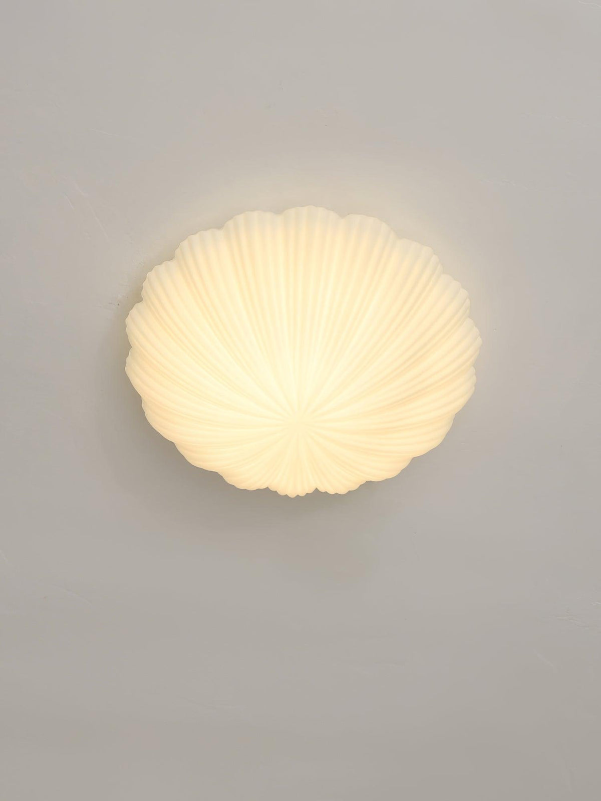 Mounted to this wall rather than a ceiling, the ribbed shade of this Clérachic light glows warm white in side profile.